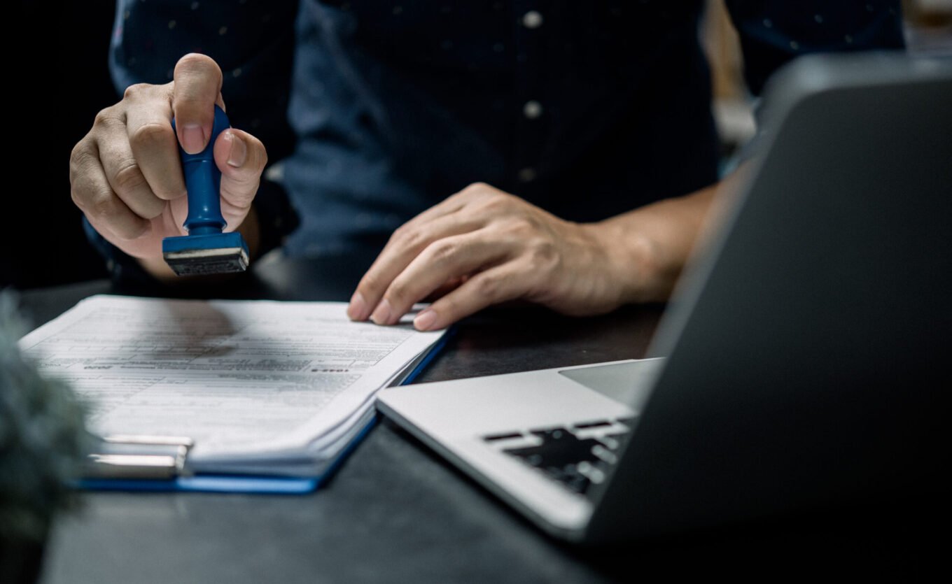 Man stamping approval of work finance banking or investment marketing documents on desk.